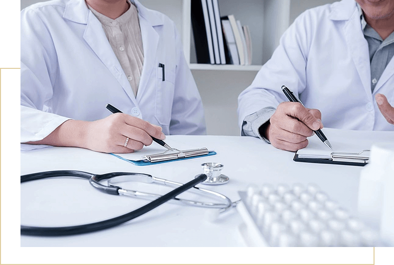 Two doctors are sitting at a table with pens and paper.